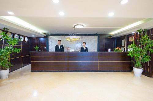 河内Sen Luxury Hotel - Managed by Sen Hotel Group的两个人站在餐馆柜台