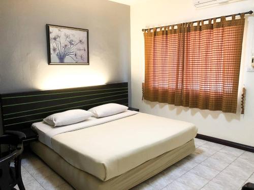 来兴府Suansin Garden Hotel โรงแรมสวนสินการ์เด้น的一间卧室设有一张床和一个窗口