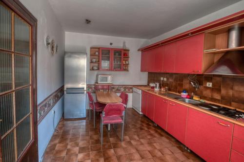 潘切沃Two Towers的一间厨房,里面装有红色橱柜和一张桌子