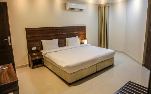 SamhānBarka Hotel Apartment的一间卧室配有一张大床和木制床头板