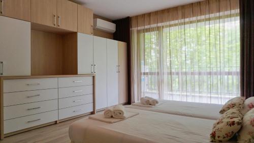 巴尔奇克Апартамент Балчик Гардънс - Balchik Gardens Apartment的一间卧室设有两张床和大窗户