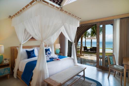 珀尼达岛The Sankara Beach Resort - Nusa Penida的一间卧室设有一张天蓬床,享有海景