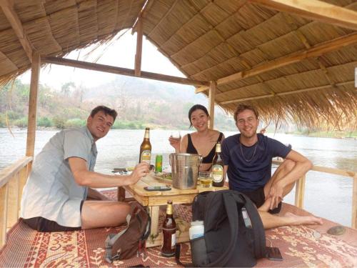 琅勃拉邦Namkhan View Luangprabang Resort的三人坐在桌子上喝啤酒
