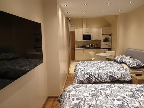 依尔福London Luxury Apartments 3 Bedroom Sleeps 8 with 3 Bathrooms 4 mins walk to tube free parking的一间带两张床的卧室和一间带桌子的厨房