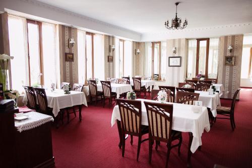 斯拉百斯宏达酒店的一间设有白色桌椅和窗户的用餐室