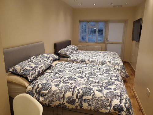 依尔福London Luxury Apartments 3 Bedroom Sleeps 8 with 3 Bathrooms 5 mins Walk to tube station free parking的一间卧室设有两张床、一个窗口和椅子