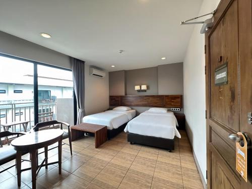 纳仲天红树林酒店 的酒店客房带两张床和一张桌子以及椅子。
