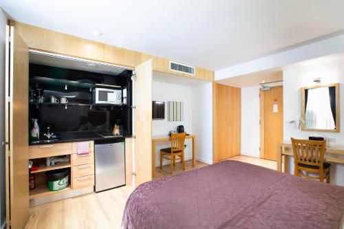 伦敦克利夫兰酒店的一间卧室配有一张床、一间厨房和一张桌子