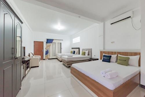 MartapuraUrbanview Hotel 99 Syariah Banjarbaru by RedDoorz的一间带两张床的卧室和一间客厅
