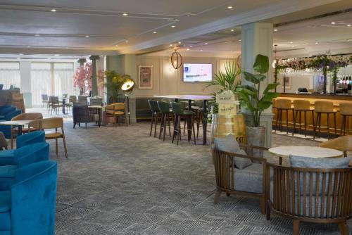 南安普敦南安普敦希尔顿逸林酒店的一间带桌椅的餐厅和一间酒吧