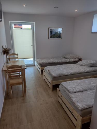 Miedziana GóraVilla na Chabrowej的客房设有三张床、一张桌子和一张桌子以及椅子。