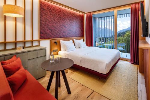 施伦斯Falkensteiner Family Hotel Montafon - The Leading Hotels of the World的酒店客房配有床、桌子和沙发。