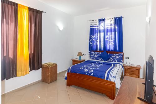 博卡奇卡Hotel Villa Capri的一间卧室配有蓝色和黄色窗帘的床