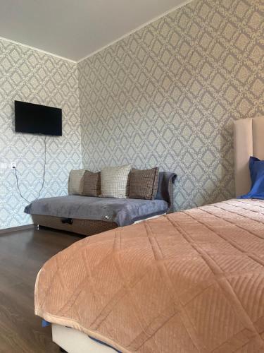 库斯塔奈Комфортабельные - Уютные апартаменты в Костанай Алтын Арман的卧室配有一张床,墙上配有电视。
