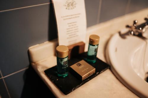 圣地亚哥－德孔波斯特拉卡萨格兰德巴乔酒店的浴室水槽和水槽旁的台面上两个瓶子