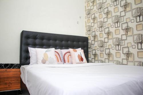 梭罗Capital O 2258 Santana Syariah Guest House的一间卧室配有带白色床单和枕头的床。