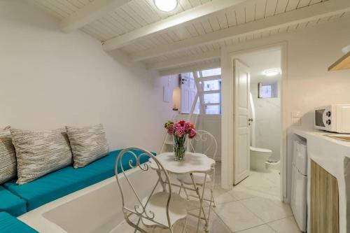伊亚The Bay - Loft apartment Sea & Sunset View的小房间设有蓝色的沙发和带鲜花的桌子