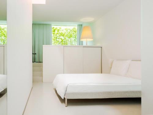 苏黎世Greulich Design & Boutique Hotel的白色卧室配有床和镜子