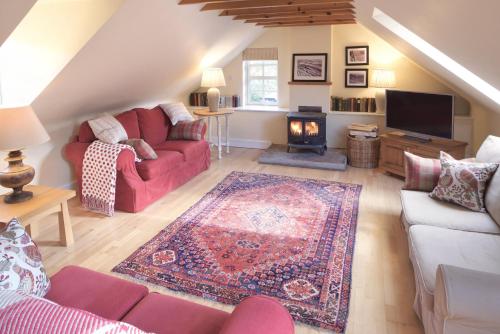 佩尼库克Eastside Byre - Family cottage in the Pentland Hills near Edinburgh的客厅设有红色的沙发和壁炉