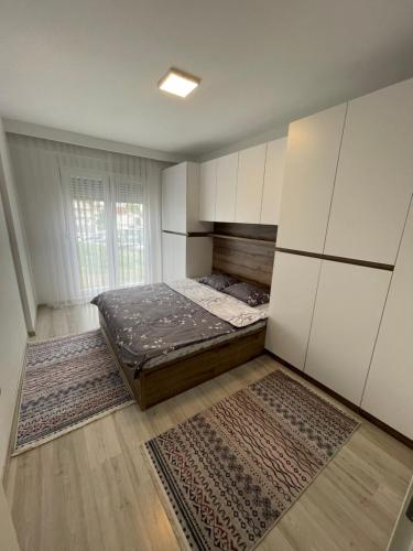普里什蒂纳Plis Apartment II的卧室配有1张床、白色橱柜和地毯。
