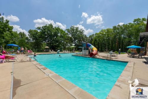 布兰森Forest Heights Lodge - 6BR - Pool Table - Near Silver Dollar City - FREE TICKETS INCLUDED的公园内的游泳池,带游乐场