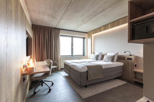 NederweertHotel Rosveld的一间卧室配有一张床、一张书桌和一个窗户。