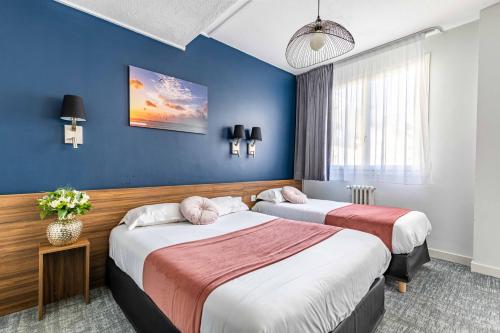 雷恩le paris brest hotel的两张位于酒店客房的床,拥有蓝色的墙壁