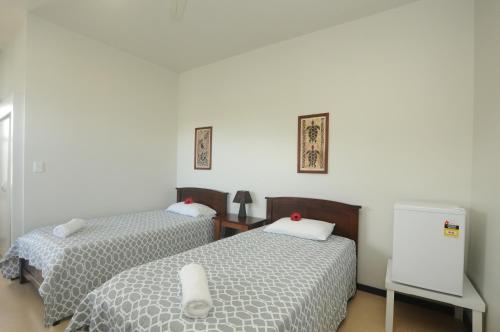 阿皮亚塔罗法酒店的一间卧室设有两张床和白色的墙壁