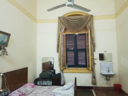 亚历山大Clement's House Hostel的一间卧室配有一张床和一个带风扇的窗户。