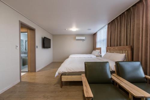 济州市艾琳酒店的一间卧室配有一张大床和两把椅子