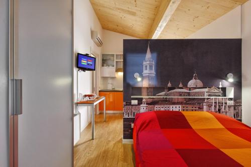法瓦罗威尼托生态威尼斯公寓的一间卧室配有一张色彩缤纷的床和一间厨房
