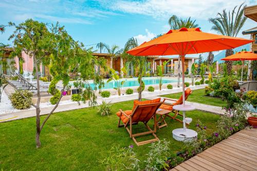 凯麦尔Cirali Hestia Lodge的一个带两把椅子和一把遮阳伞的庭院和一个游泳池