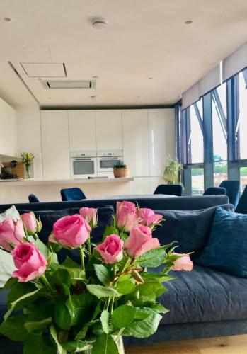伦敦Luxury 2 bedroom apartment 20 min from central London的蓝色的长沙发,上面有一束粉红色玫瑰花
