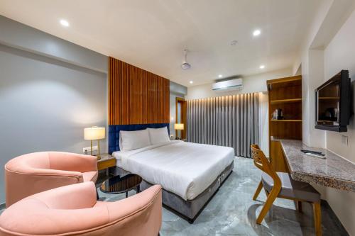 艾哈迈达巴德那兰陀酒店的酒店客房,配有一张床和两把椅子