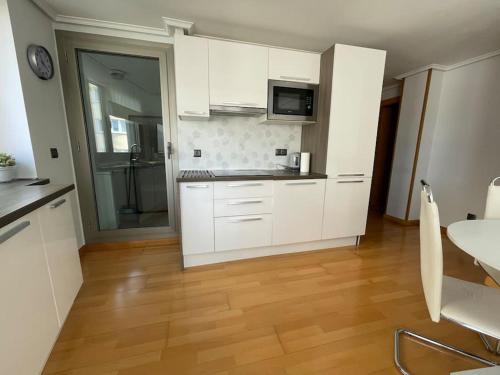 乌迪亚莱斯堡Ostende Beach View apartment的厨房铺有木地板,配有白色橱柜。