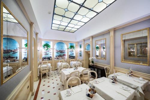 威尼斯哥伦比亚酒店的餐厅设有白色的桌椅和天窗