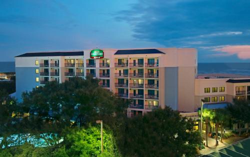 可可比奇Courtyard by Marriott Cocoa Beach Cape Canaveral的酒店大楼的顶部有一个绿色标志