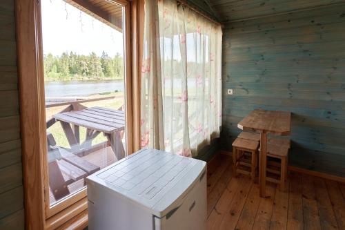 ZutēniJuku Dzirnavas的小屋内带桌子和窗户的房间