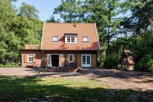 卢特伦Fantastisch familiehuis met grote tuin I Bosrijk的院子中一座红色屋顶的小房子
