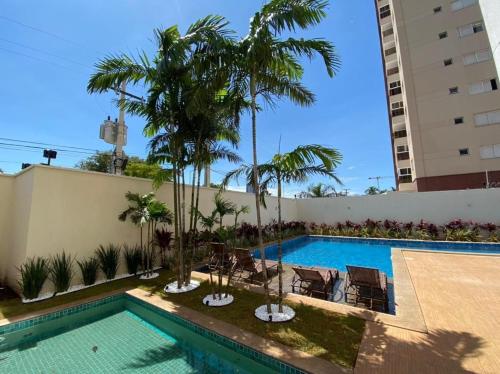 帕尔马斯Apartamento Horizonte Azul, vista lago, próximo ao shopping的一座棕榈树游泳池,位于酒店大楼旁