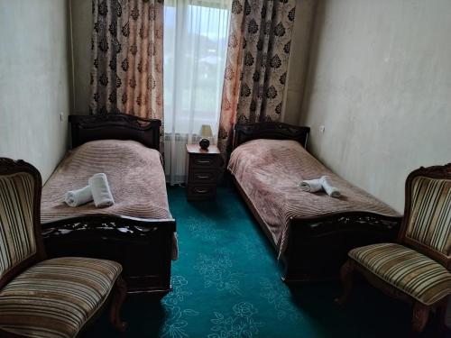 GarniGarni Guesthouse的配有两张床铺的客房,设有两把椅子和一扇窗户