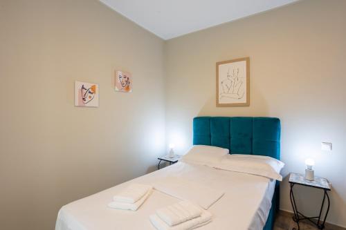 美西尼Luxury & Cozy apartment的一间卧室配有一张带蓝色床头板的床和2条毛巾