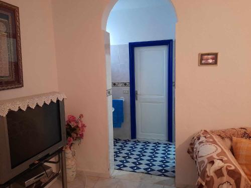 海尔盖莱Maison à Hergla, Sousse, Tunisie的一间带电视的客厅和一扇铺有瓷砖地板的门
