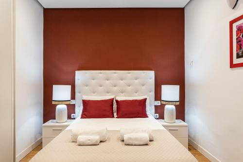 马德里BNBHolder Apartamentos en Sol Superior 2的卧室配有带红色枕头的大型白色床