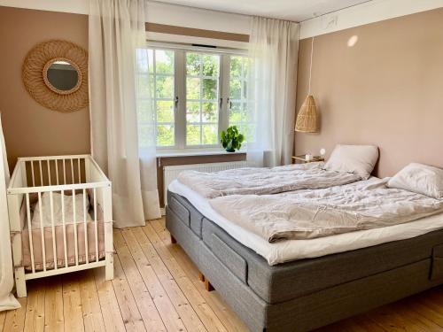 科尔莫登Villa Rye Street Kolmården的一间卧室设有一张床、一个窗口和一张婴儿床