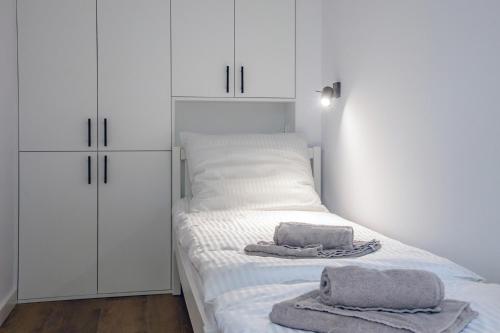 瓦尔米亚地区利兹巴克Apartament Alpaka 1的卧室配有白色橱柜和床上毛巾