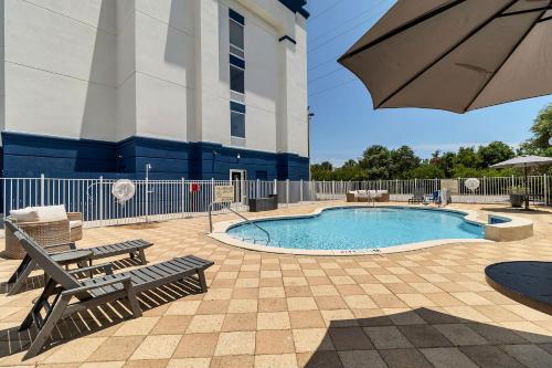 德斯坦Evoke Destin Hotel的大楼旁的带长椅和遮阳伞的游泳池