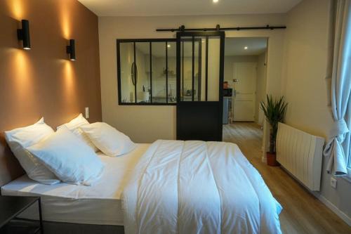 索姆河畔的圣瓦列里Appartement Saint-Valery的卧室配有白色床和墙上的镜子