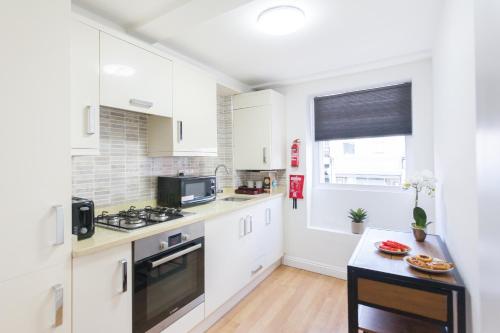 伦敦Holloway Budget Apartment - 1 Minute to Emirates Stadium - Next to Station - City Center的厨房配有白色橱柜和炉灶烤箱。