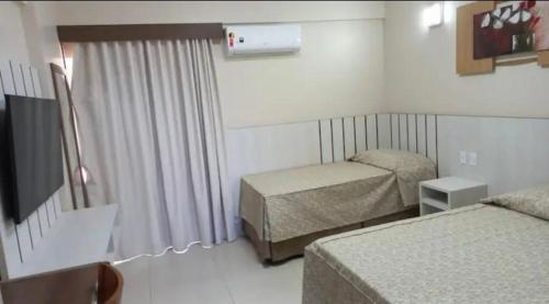 卡达斯诺瓦斯SPAZZIO Andrian & Silva - INCLUSOS INGRESSOS DO PARQUE的酒店客房设有两张床和电视。